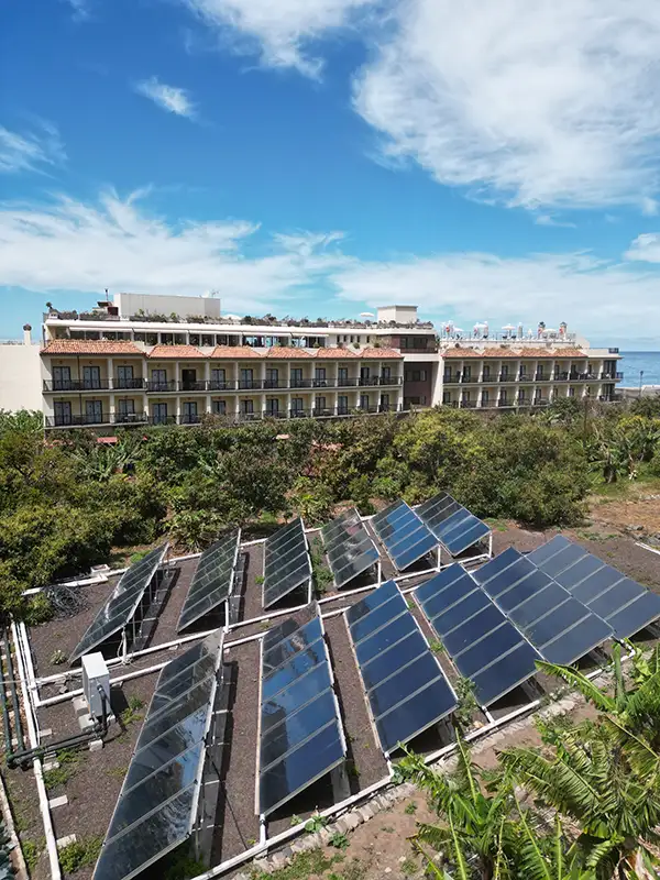 Edificio costero con paneles solares instalados en primer plano y cielo azul.