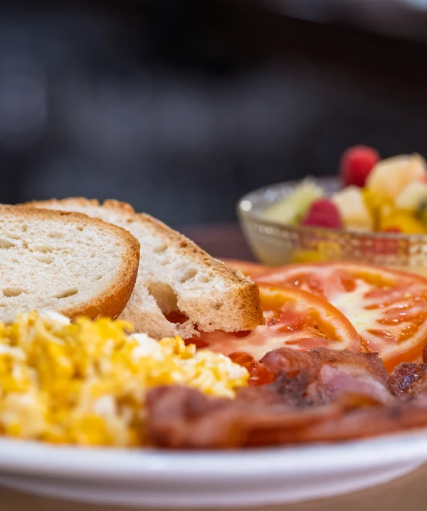 Tosta con huevo revuelto, tomate y ensalada, en un plato.