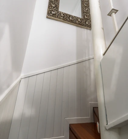 Escalera interior blanca con barandilla y pared con marco dorado