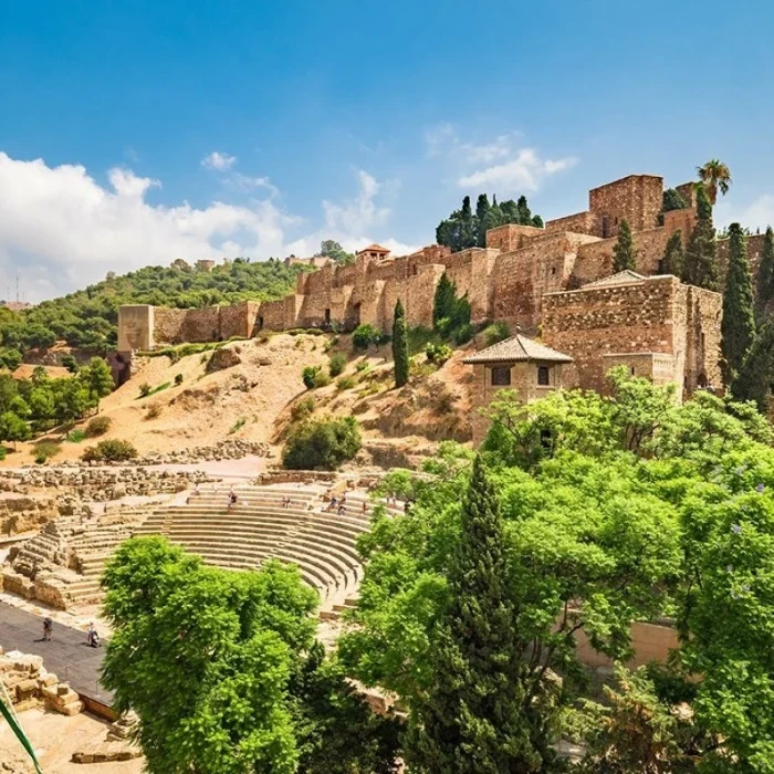 Ruinas de un anfiteatro y murallas de piedra con vegetación y cielo azul