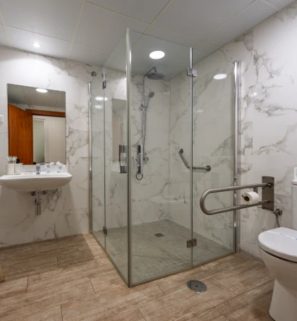 Ba&ntilde;o moderno con ducha de cristal, lavabo y suelo de madera.