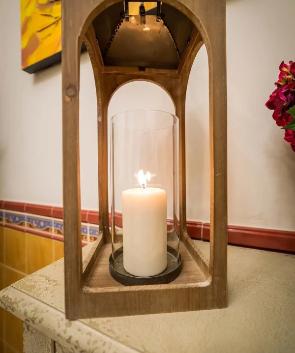 Farol de vidrio con vela encendida en un nicho de madera decorativa