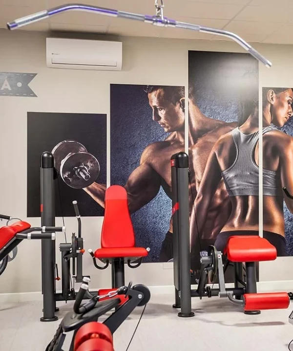 Gimnasio con m&aacute;quinas de pesas y carteles de atletas en la pared.