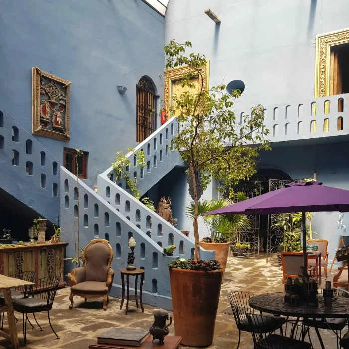 Patio interior con escaleras de ladrillos, plantas y mesa bajo sombrilla.