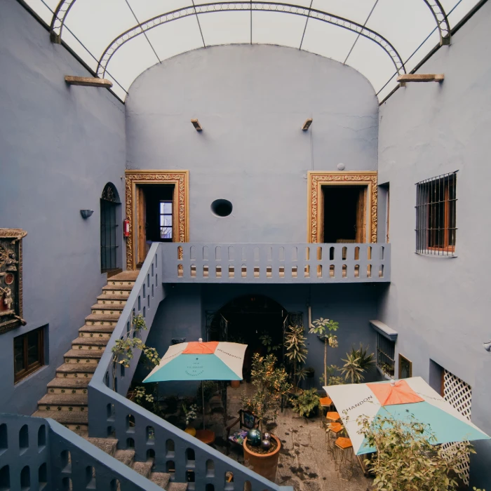 Patio con escaleras, sombrillas y dos puertas en un edificio blanco.
