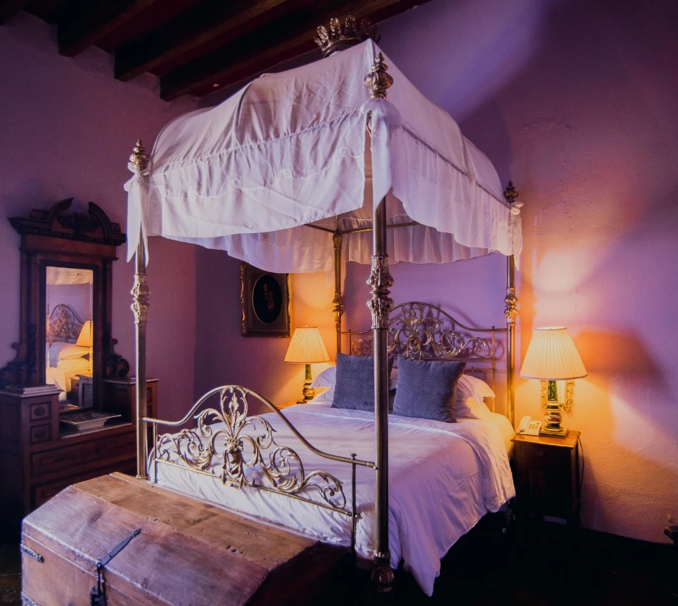 Cama con dosel blanco y luces c&aacute;lidas en dormitorio r&uacute;stico decorado