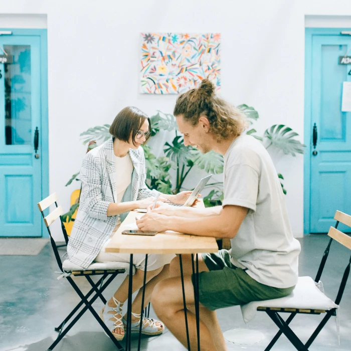 Dos personas trabajando y escribiendo en una mesa, en un estudio luminoso