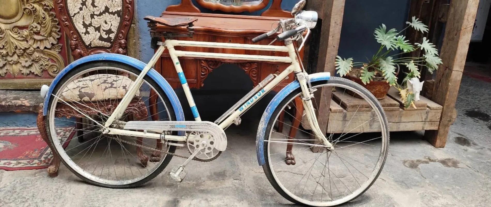Bicicleta blanca con llantas azules junto a un arco de madera en la calle
