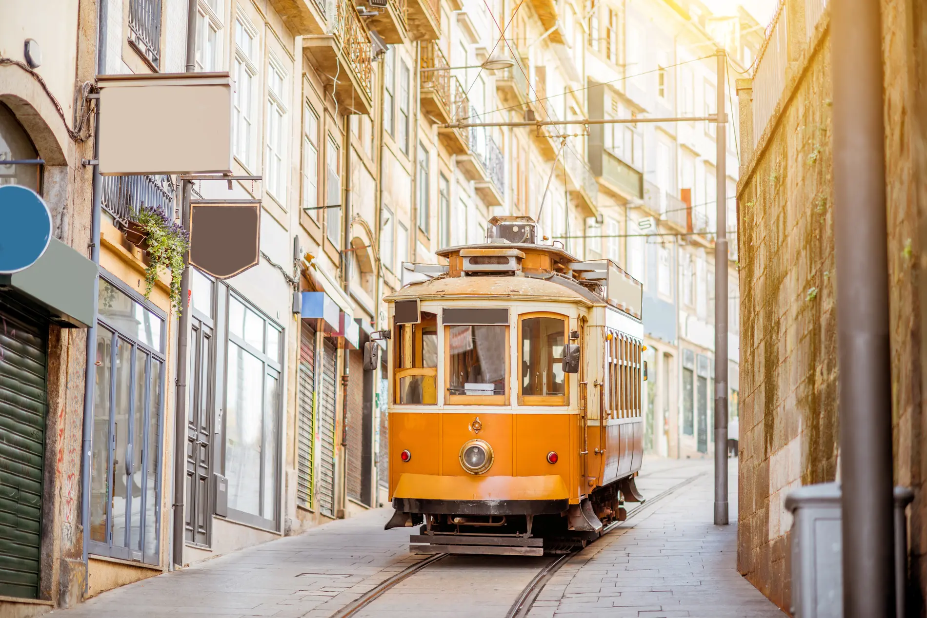 Vag&atilde;o amarelo de bonde em rua estreita com pr&eacute;dios hist&oacute;ricos