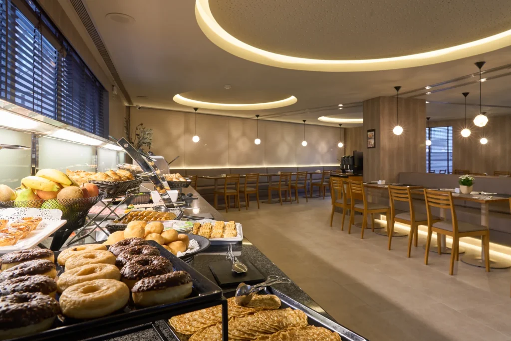 Buffet de caf&eacute; da manh&atilde; com p&atilde;es e sal&atilde;o iluminado por luzes LED indiretas