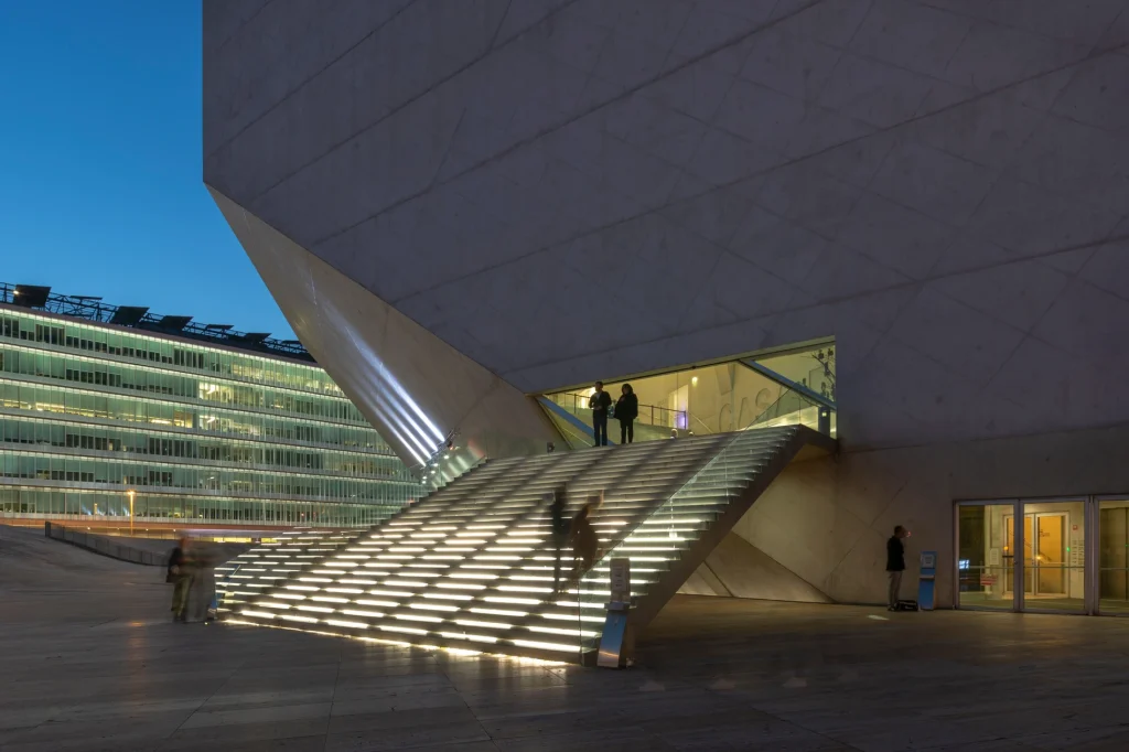 Escadaria iluminada e fachada moderna em edif&iacute;cio p&uacute;blico ao entardecer