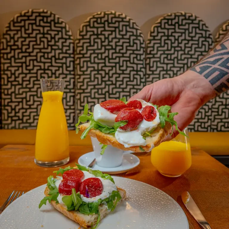 Camarero sirve brusquetas con mozzarella y salami sobre mesa con jugos.