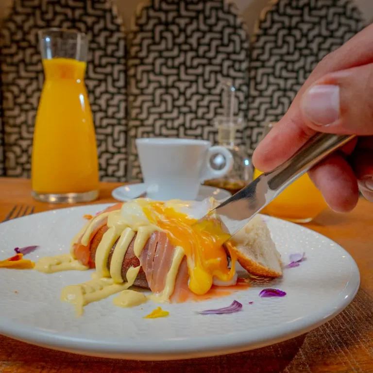 Camarero corta un s&aacute;ndwich con queso derretido y salsa amarilla en plato