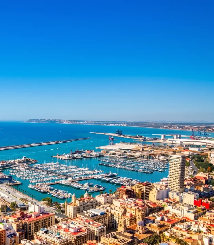 Panor&aacute;mica de un puerto mar&iacute;timo con barcos y edificios junto al mar azul.