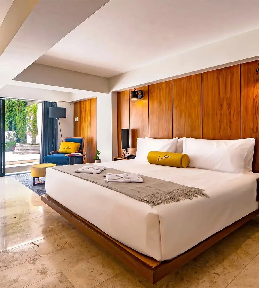 Dormitorio moderno con cama doble, cabecero de madera y almohadas amarillas