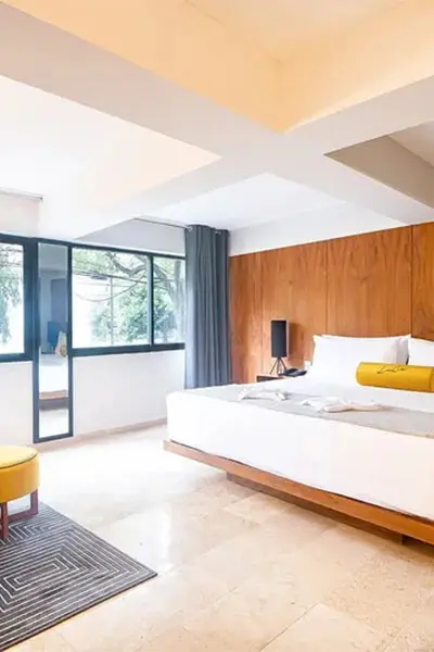 Dormitorio moderno con cama, ventana panor&aacute;mica y pared de madera.