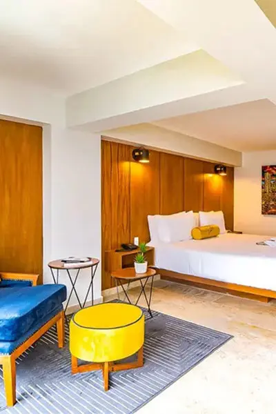 Interior moderno con cama, sill&oacute;n amarillo y l&aacute;mparas c&aacute;lidas en habitaci&oacute;n