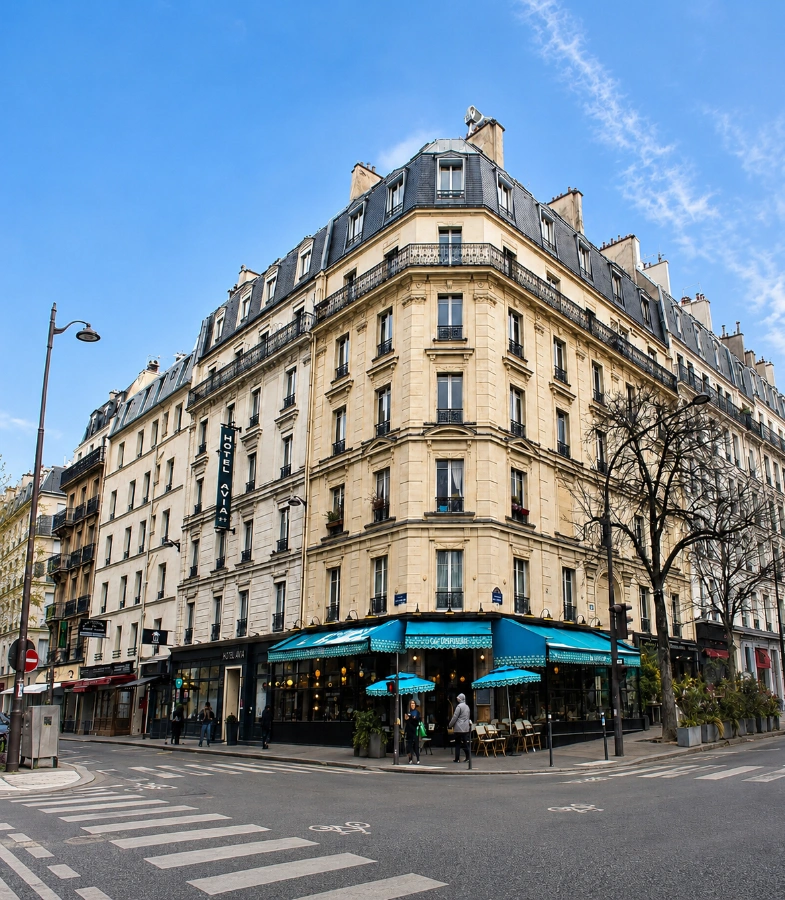 Immeuble haussmannien avec terrasse au coin de rue, ciel bleu en arri&egrave;re-plan.