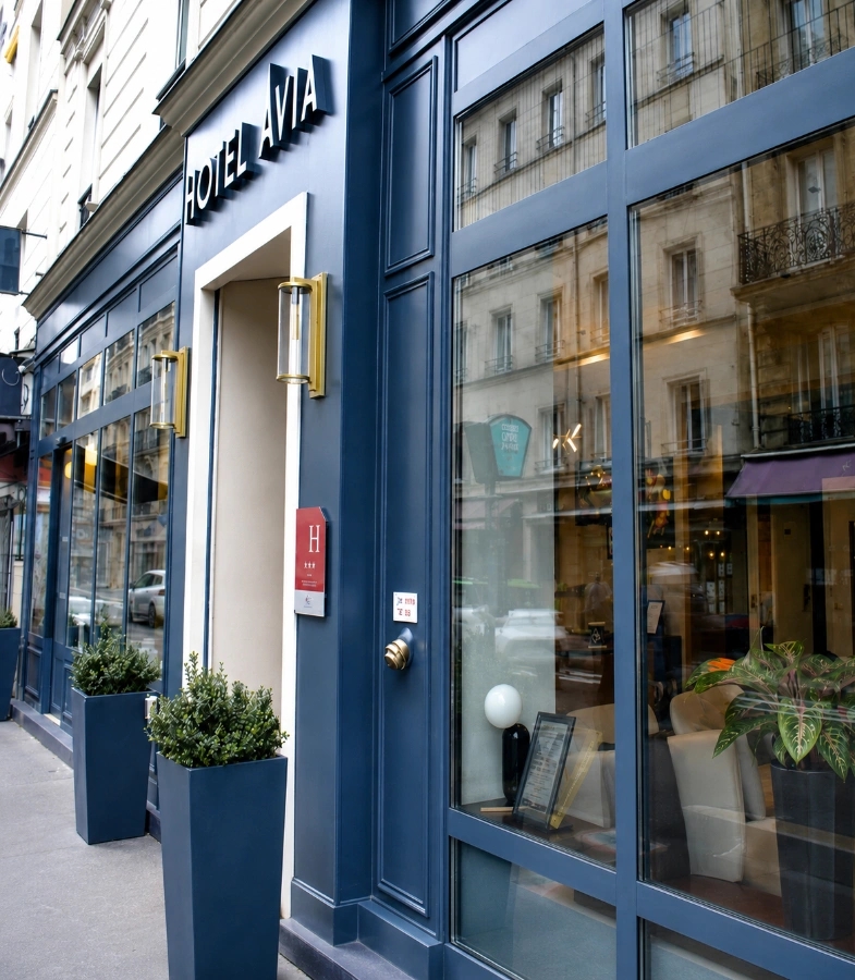Fa&ccedil;ade d&rsquo;h&ocirc;tel Via, entr&eacute;e avec enseigne et fen&ecirc;tres bleues sur rue parisienne