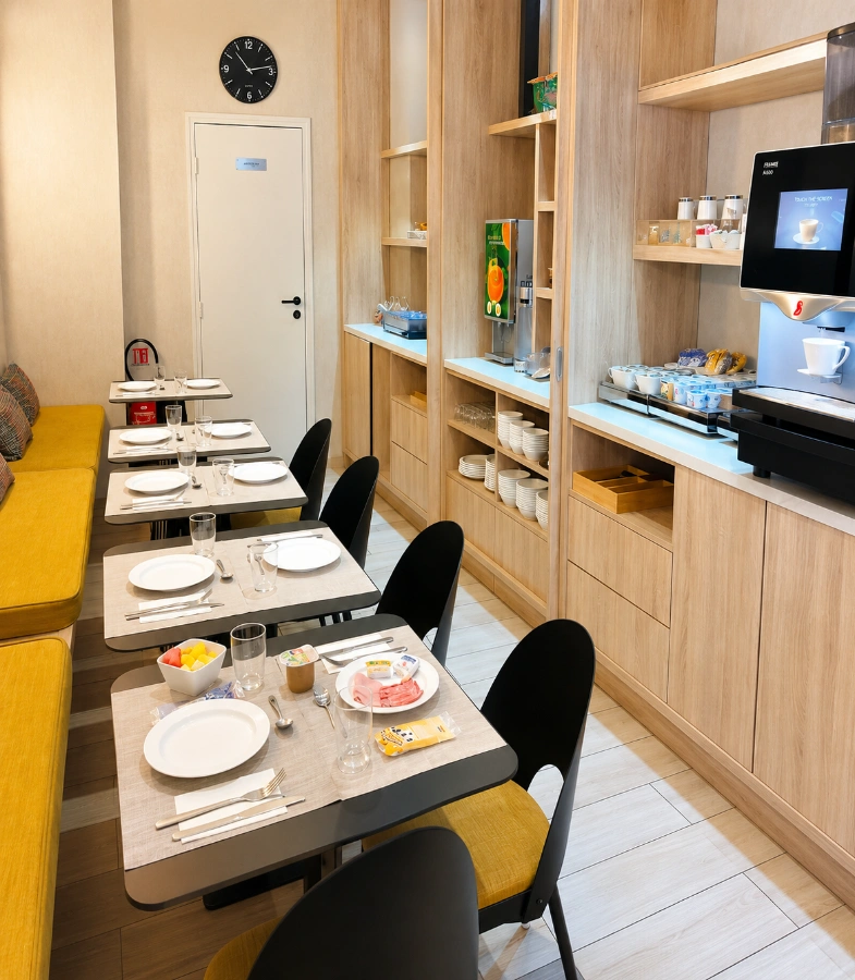 Salle de petit-d&eacute;jeuner moderne avec tables dress&eacute;es et buffet en bois