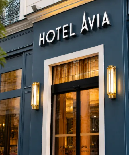 Enseigne &laquo; H&ocirc;tel AVIA &raquo; sur la fa&ccedil;ade d&rsquo;un h&ocirc;tel, &eacute;clair&eacute;e le soir.