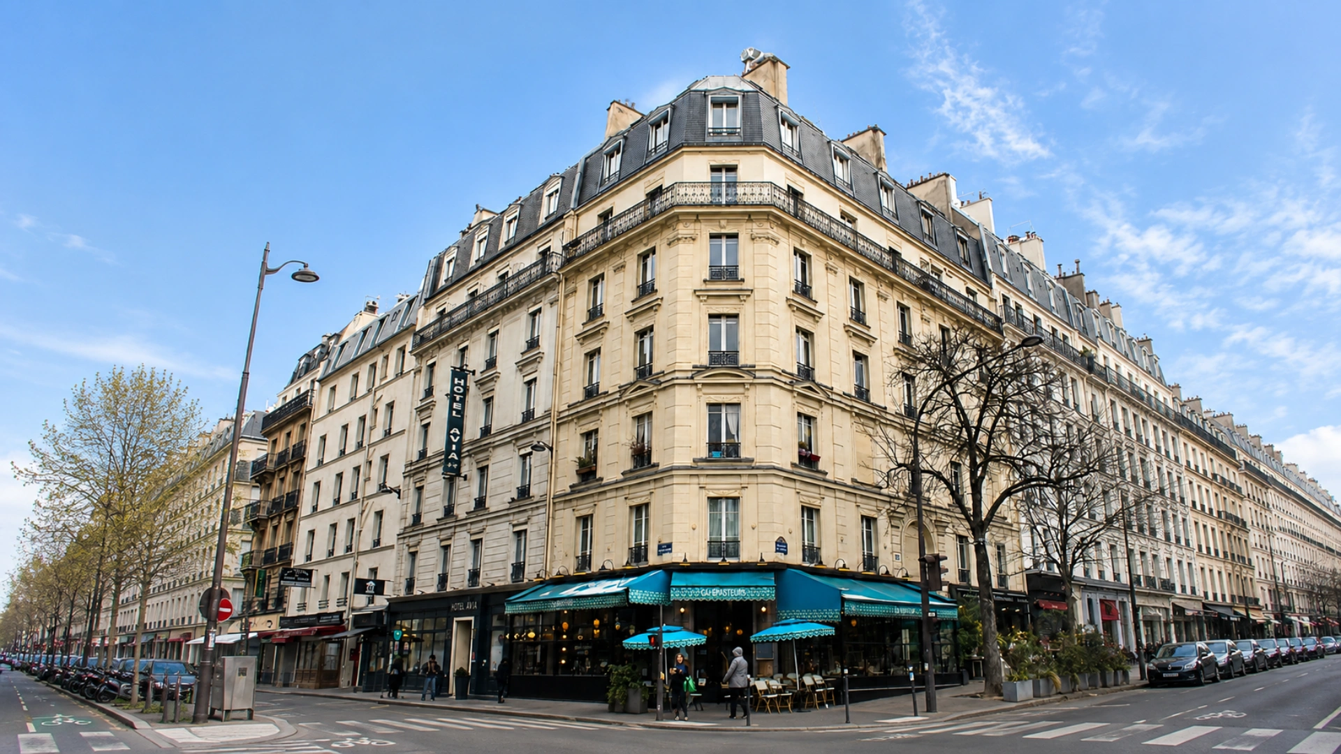 Fa&ccedil;ade d&rsquo;immeuble parisien avec caf&eacute; et passants, ciel bleu d&eacute;gag&eacute;