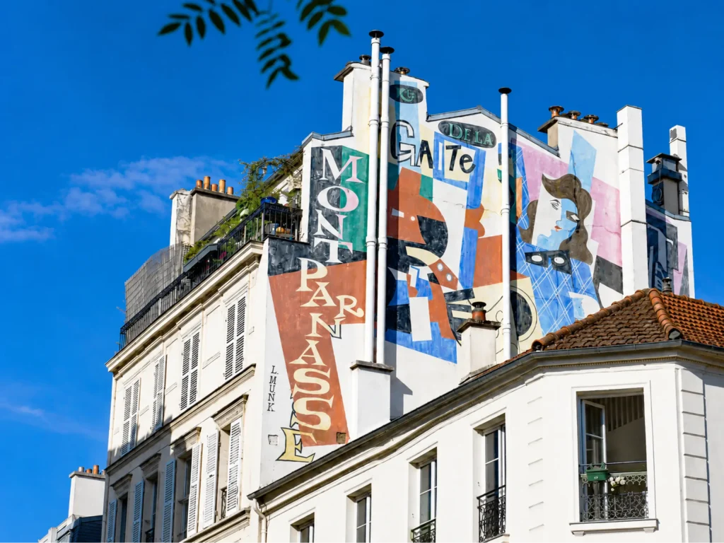 Fa&ccedil;ade d&rsquo;immeuble avec fresques color&eacute;es et chemin&eacute;es sous ciel bleu