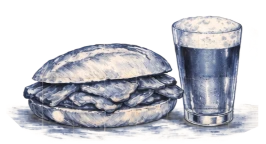 Stacked blue quilts with a metal cup on a snowy surface