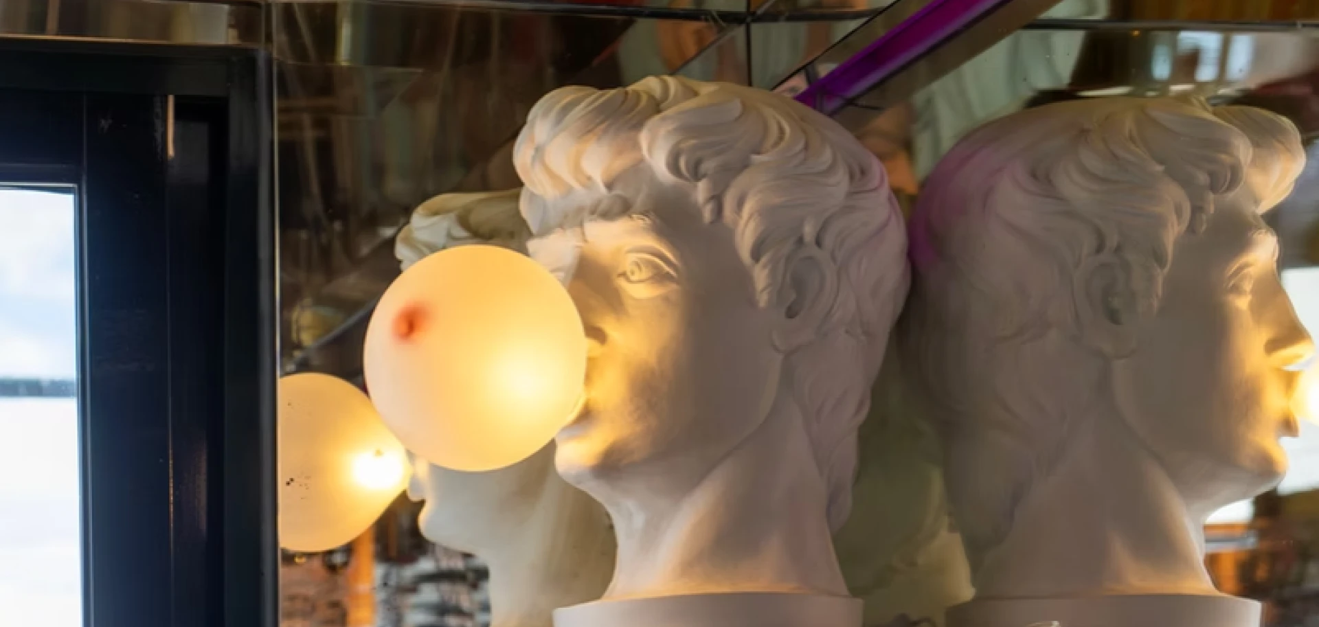 Stone bust sculptures with a glowing display indoors, seen in profile and close-up