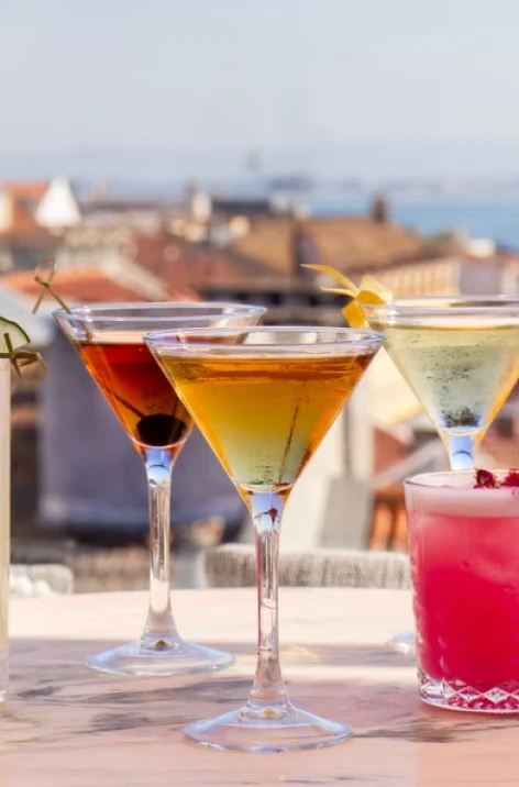 Colorful cocktails in martini glasses with lemons on a seaside table