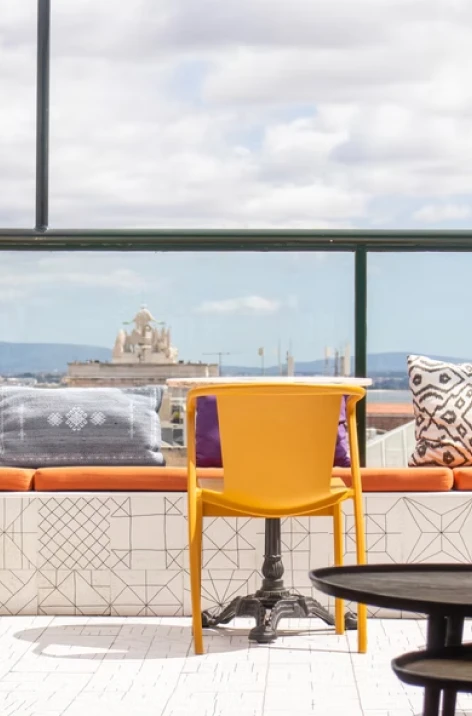 Yellow chair on tiled patio with couches, coffee table, and cloudy view