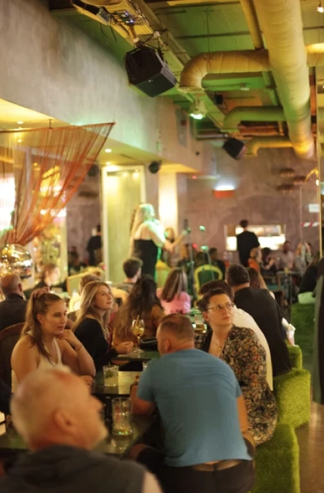 People dining and chatting in a warmly lit restaurant with green decor