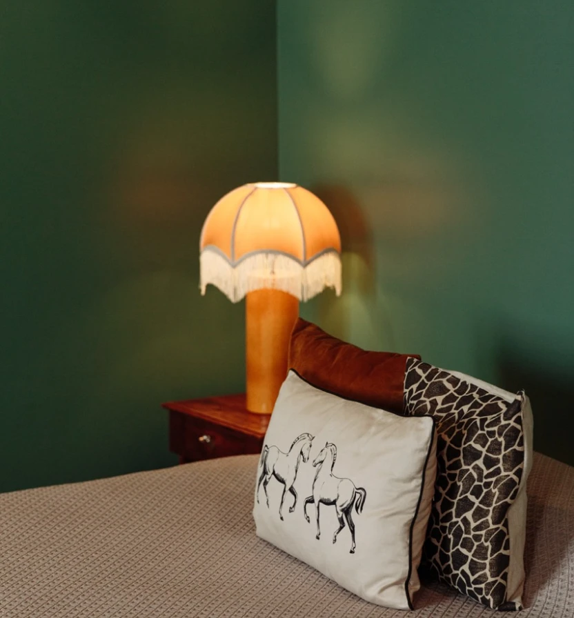 Brown-and-white pillows with giraffe print and yellow umbrella lamp on table