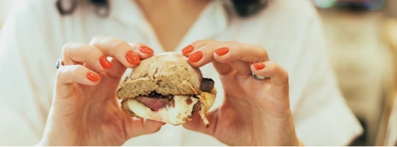 Hands holding a bitten pastry with chocolate filling, close-up view