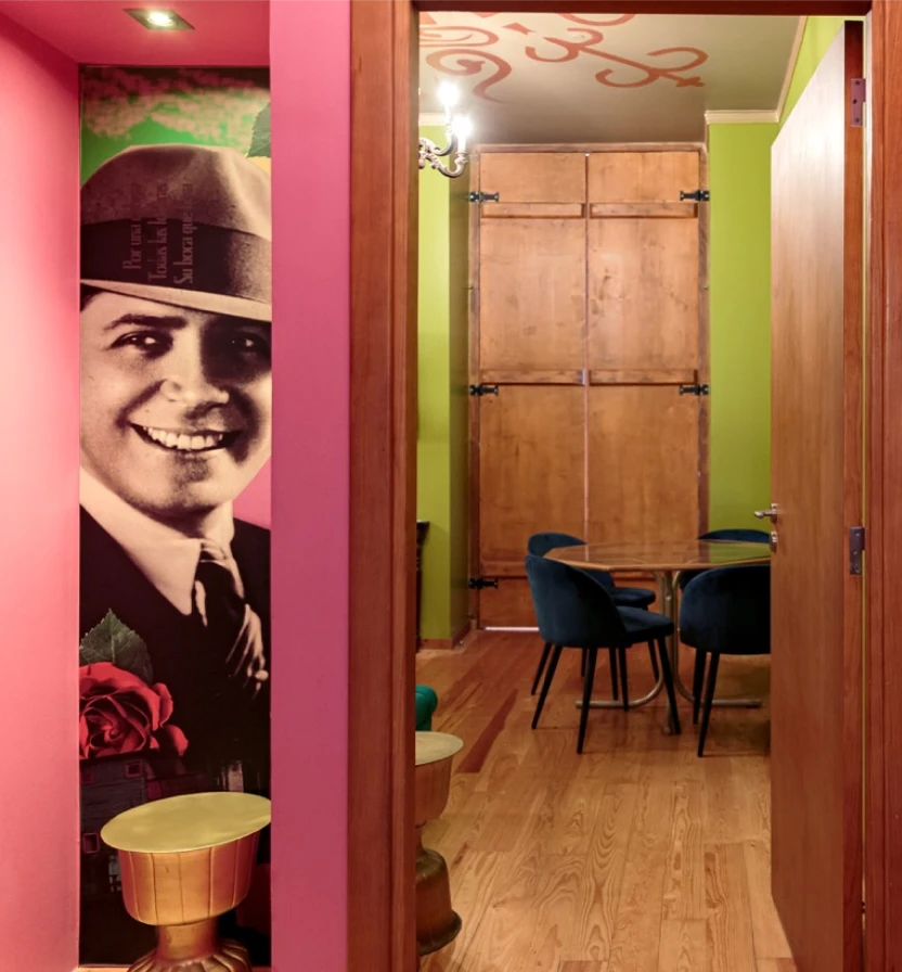 Hallway view with framed portrait, green walls, wooden floor, and dining table