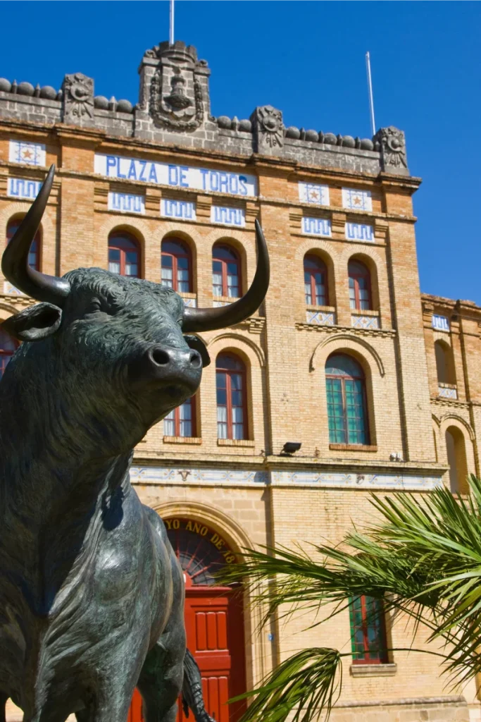 Escultura de toro frente al edificio &ldquo;Plaza de Toros&rdquo; bajo cielo azul