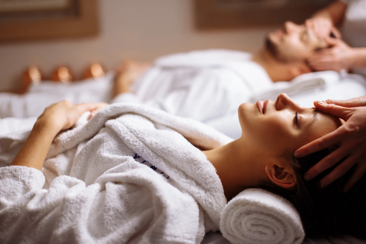 Masaje relajante en spa, persona con toalla blanca y manos sobre el rostro