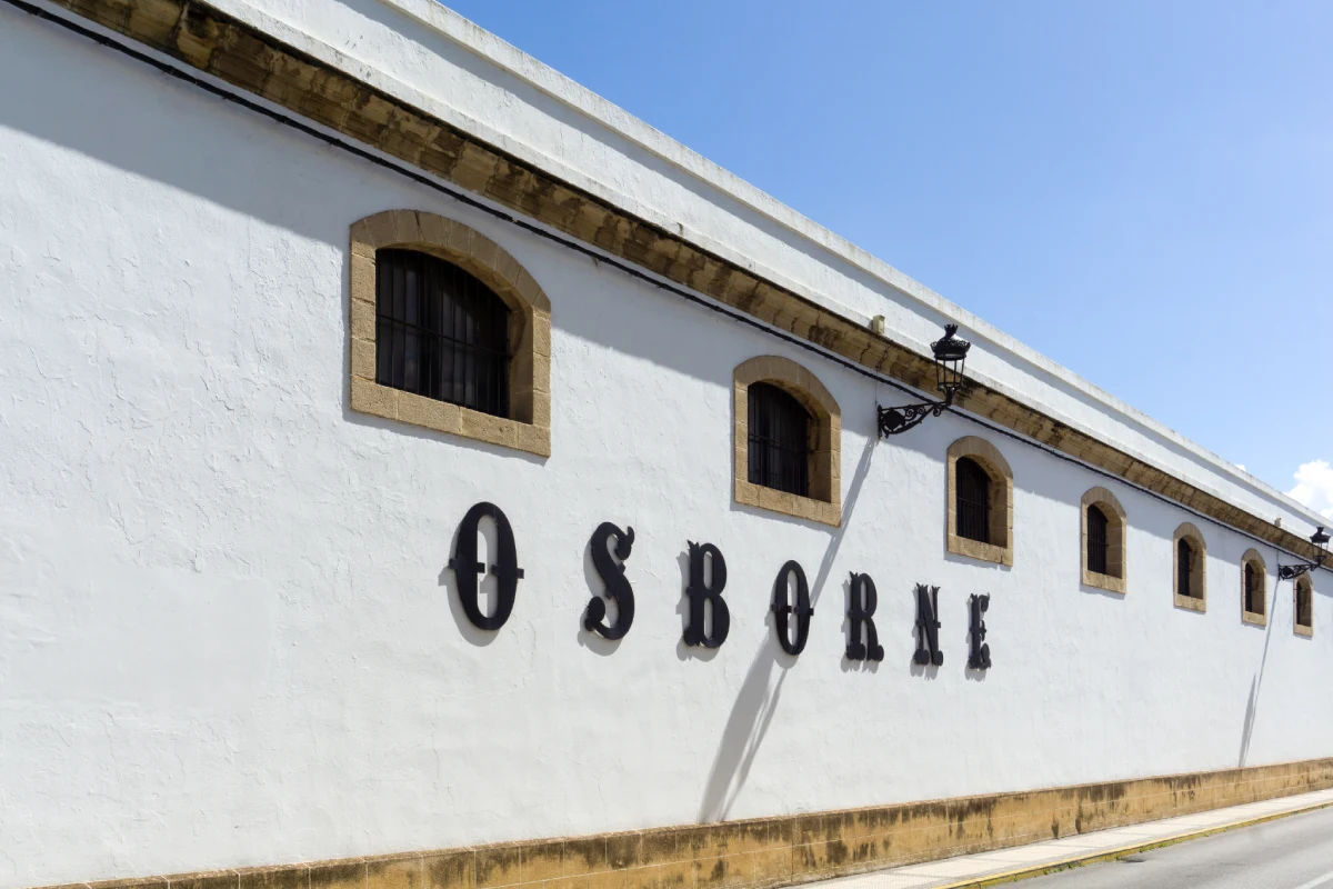 Fachada blanca con ventanas y letras &ldquo;SBRORN&rdquo;, con cielo azul.