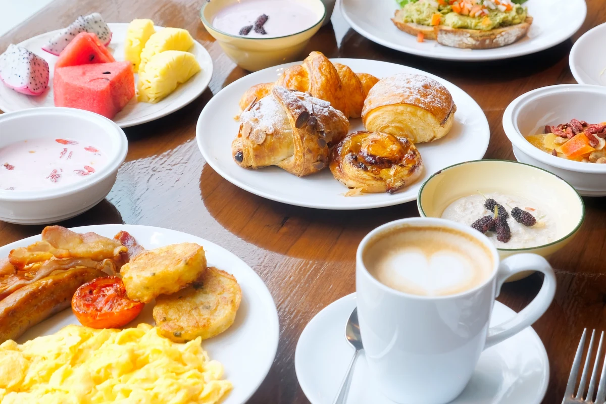 Desayuno con croissants, fruta fresca y tazas de caf&eacute; con crema