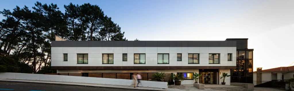 Edificio moderno de oficinas con ventanas y jard&iacute;n, vista exterior al atardecer