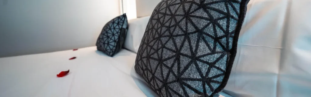 Almohadas con funda negra y dise&ntilde;o geom&eacute;trico, en sof&aacute; blanco.