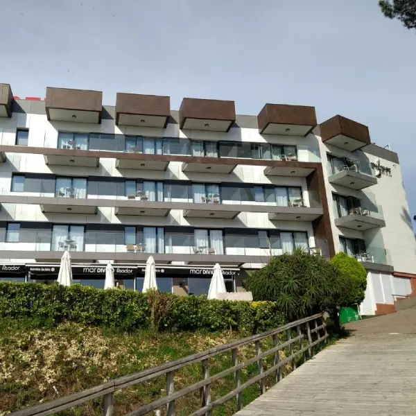 Edificio residencial con balcones y ventanales, camino de acceso y jard&iacute;n