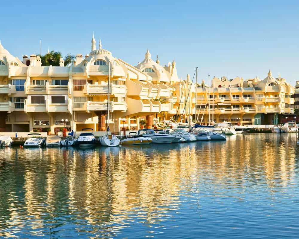 Puerto con barcos y edificios blancos estilo mediterr&aacute;neo junto al mar