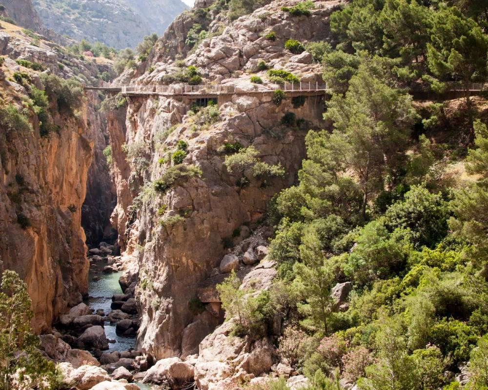 Puente sobre ca&ntilde;&oacute;n rocoso con r&iacute;o y vegetaci&oacute;n en la ladera monta&ntilde;osa