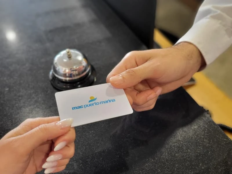 Entrega de una tarjeta &ldquo;mac puerto marina&rdquo; en un mostrador, manos y timbre