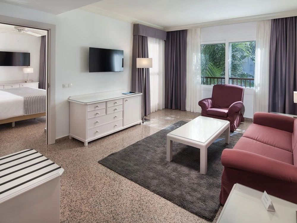 Sala de estar moderna con sof&aacute;, sill&oacute;n, mesita y cortinas.