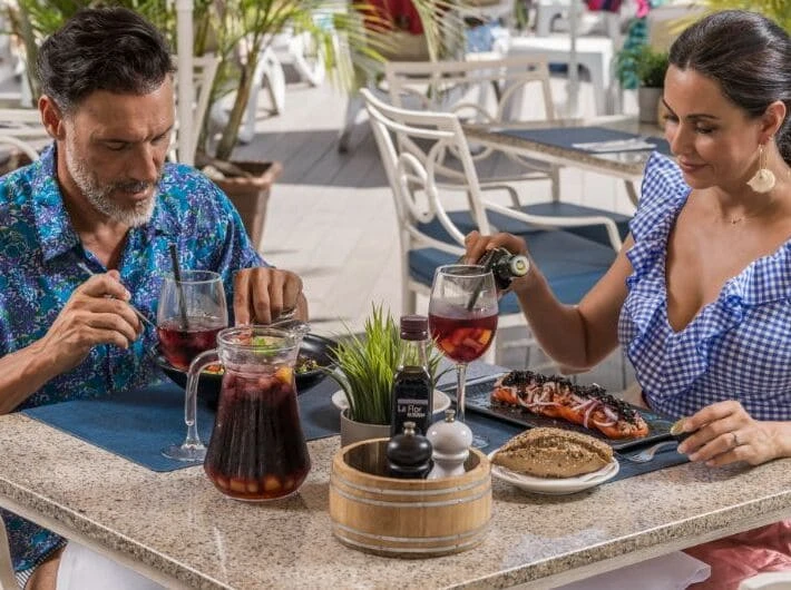 Pareja desayunando en la terraza con copas de vino y parrillada.