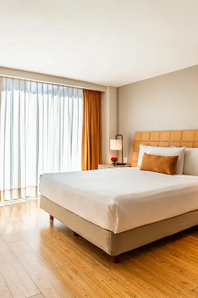 Dormitorio moderno con cama, l&aacute;mpara y cortinas junto a la ventana