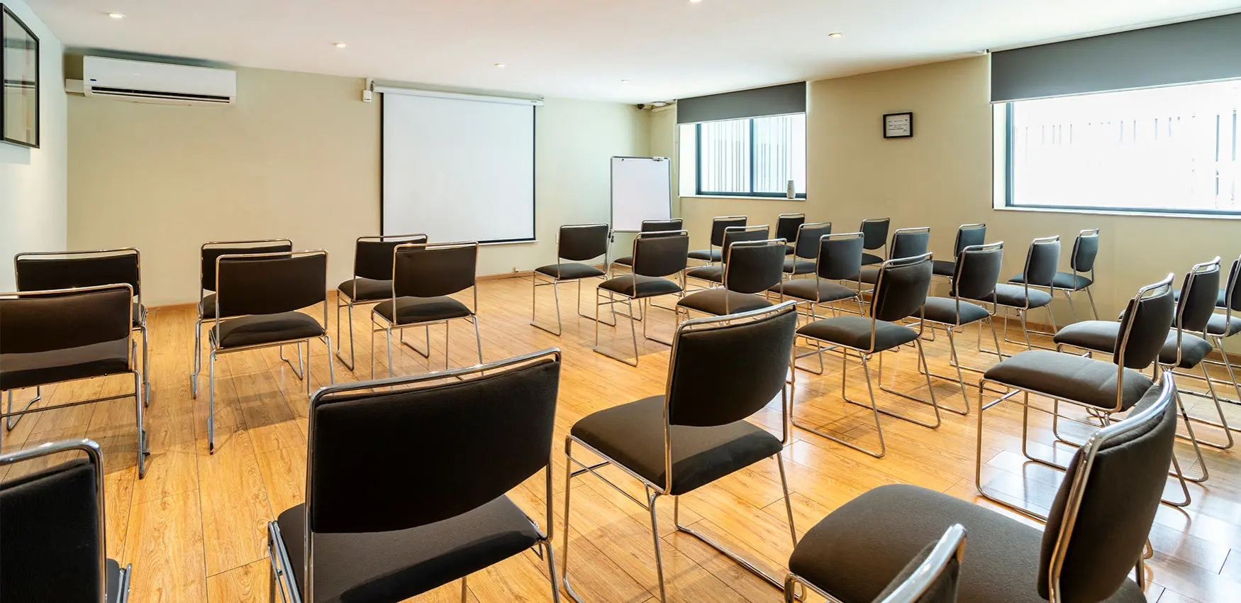 Sala de conferencias con sillas modernas y pantalla de proyección al fondo