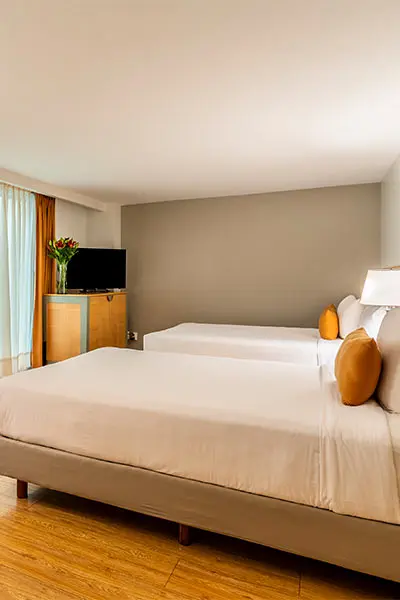 Habitaci&oacute;n de hotel con cama, mesita y l&aacute;mpara de pie